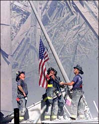 Firemen raise flag over WTC rubble.